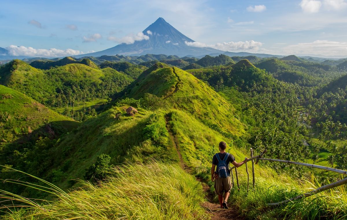 Hiker,With,Backpack,Looks,At,The,View,On,The,Mayon