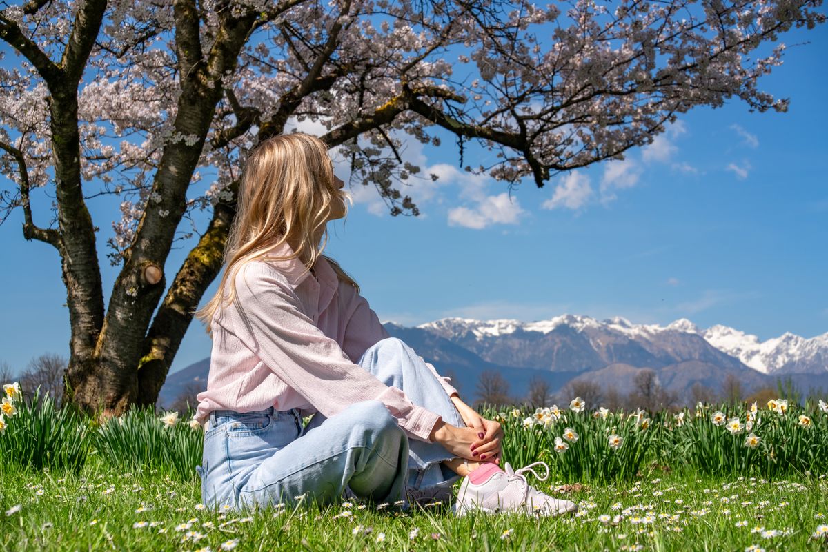 Young,Woman,Meditating,Under,A,Cherry,Blossom,Tree,With,Snowy